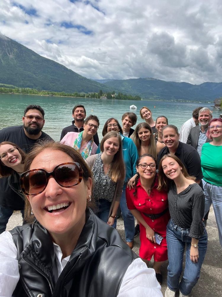 A group selfie in front of the lake Wolfgangssee in Strobl, Austria. Lots of smiling faces. 
