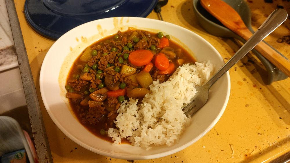 Japanese golden curry with jasmine rice with ground beef, mushrooms, potatoes, carrots, peas, and apple pieces