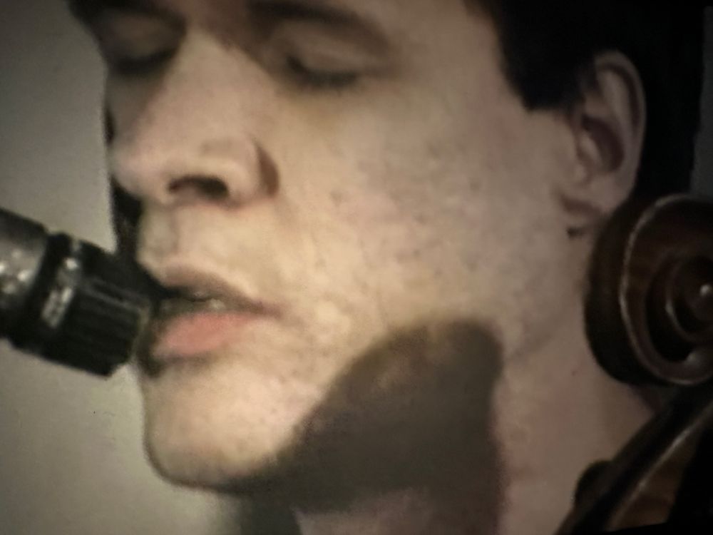 Close up video capture of Arthur Russell singing into a microphone