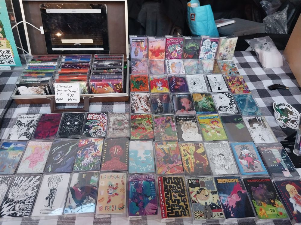 Large spread of indiepoclaypse game anthology cassette case physical editions with some in an old cassette tape briefcase