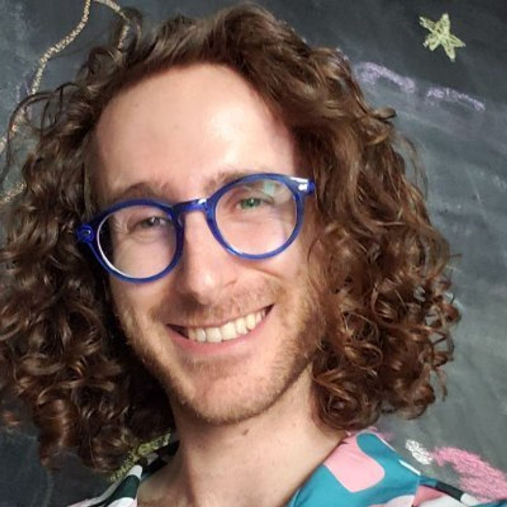 photo of a person with glasses smiling at the camera
