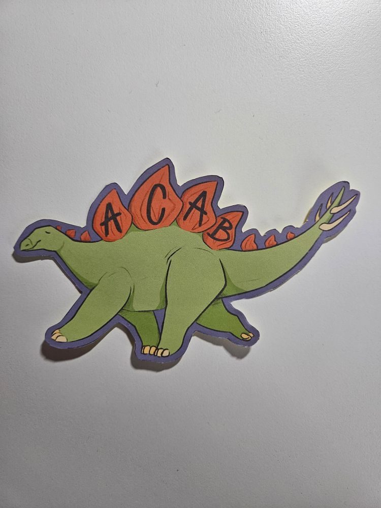 Ein grüner Stegosaurus trottet mit entspanntem Gesichtsausdruck nach links. Auf den orangenen Rückenplatten ist "ACAB" in schwarz geschrieben.