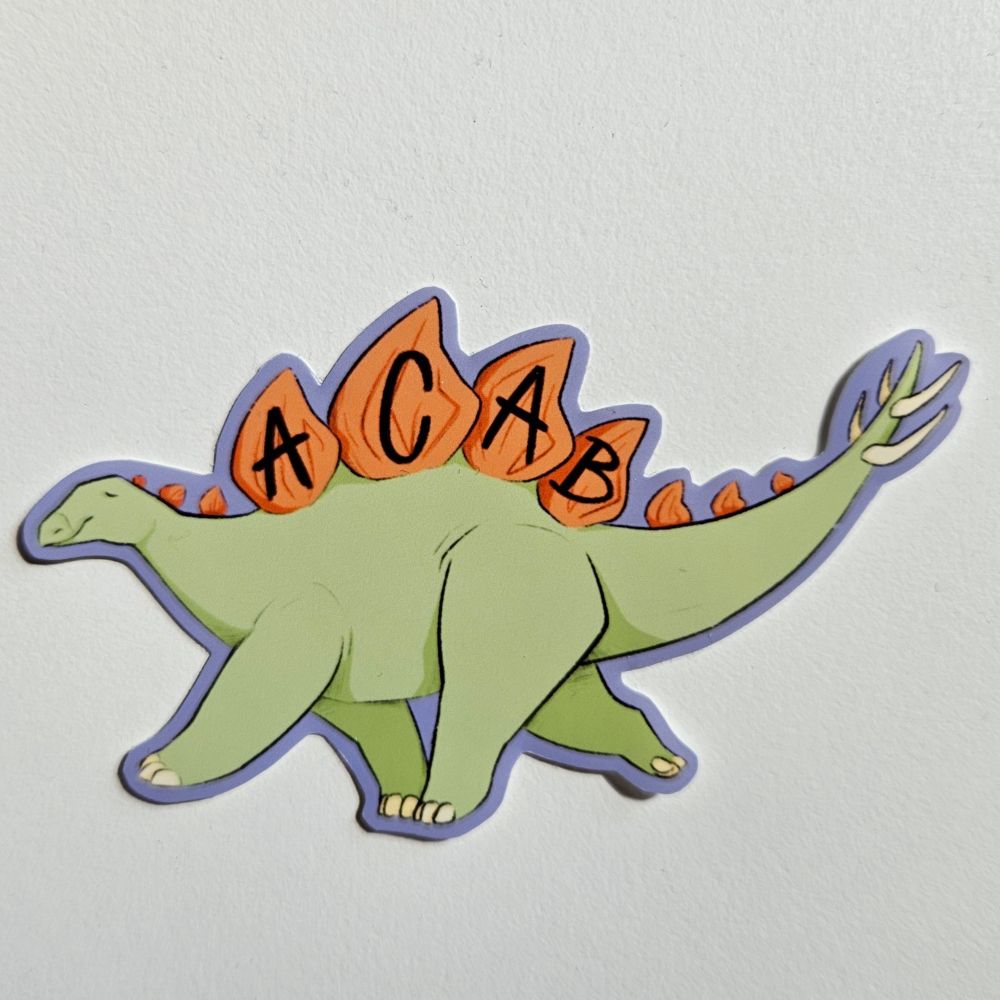 A sticker of a light green stegosaurus with "ACAB" written across it's orange back plates.