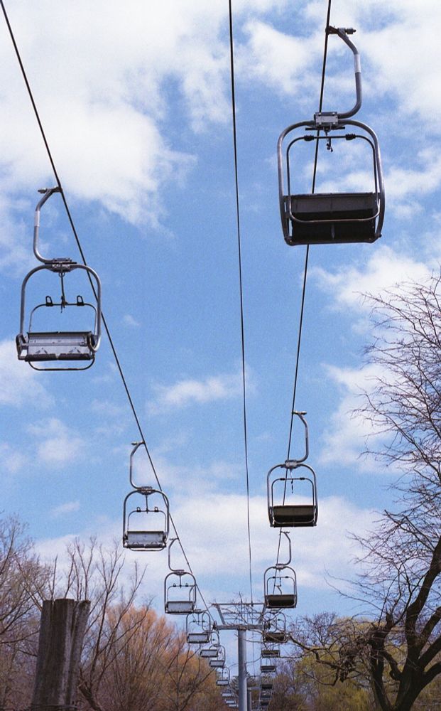 empty gondolas against a blue sky with clouds