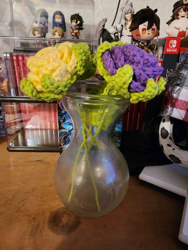 Crochet roses in colors yellow and purple inside a glass vase