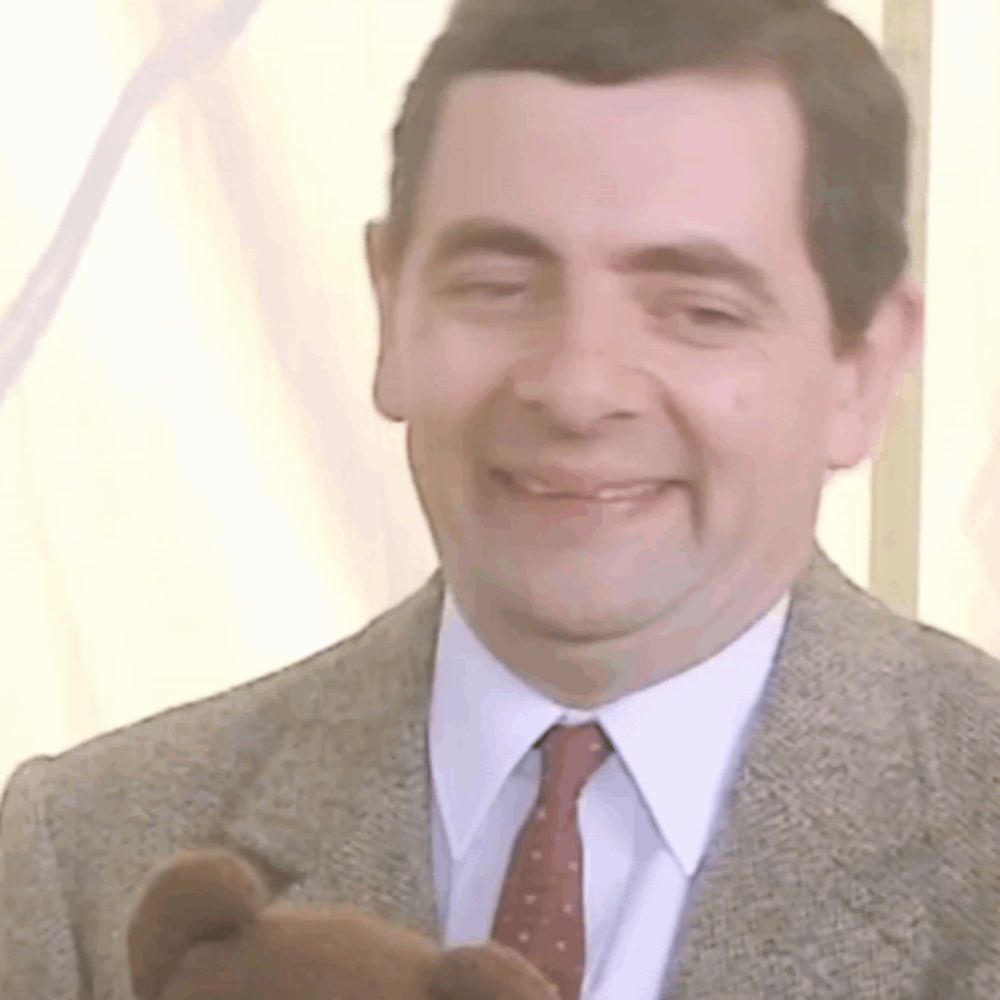 a man wearing a suit and tie is holding a teddy bear .