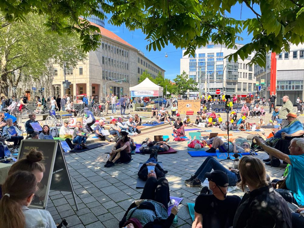 Liegend Demo auf dem Holzmarkt Jena. Teilnehmende sitzen und liegen auf dem Boden. 