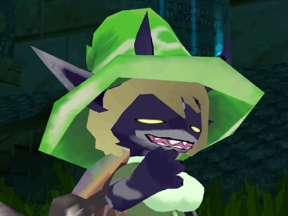 A picture of a character from Atlyss. They have two-tone purple skin, narrowed yellow eyes, straw-coloured hair, pointed teeth, long pointy ears and dark horns. They're wearing a bright green wizard's hat and a two-tone shirt. They're holding up a hand to their face in a thoughtful manner with an open mouth and eyes that look like they should be closed.