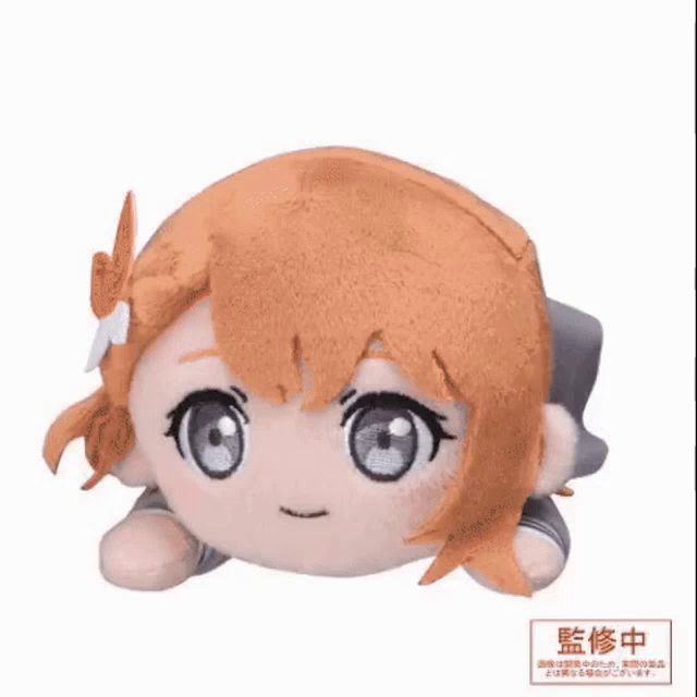 a stuffed animal of a girl with orange hair is laying on a white surface .