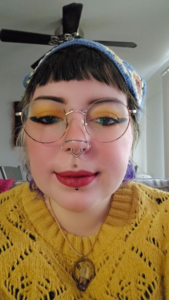 a selfie of jobee with yellow eyeshadow, big black eyeliner wings, and red lipstick on