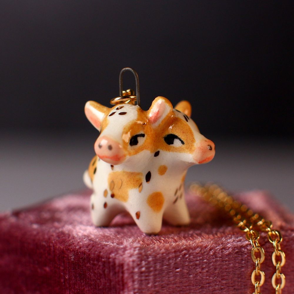 Ceramic Two headed cow pendant with gold details. 
