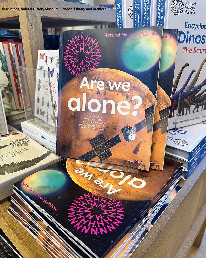 Pile of magazines on display surrounded by books.