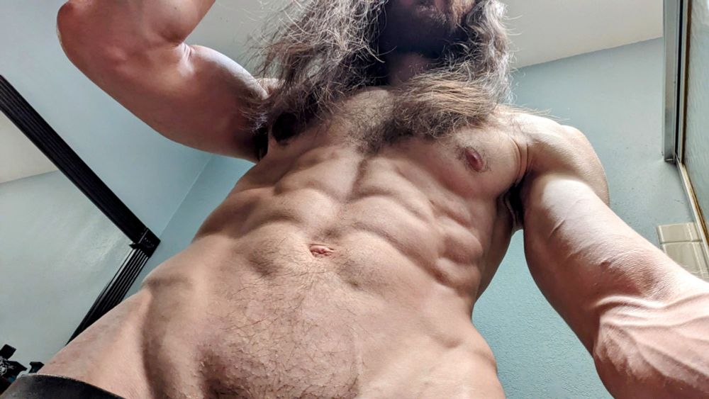 Looking up at a fit shirtless male with long hair