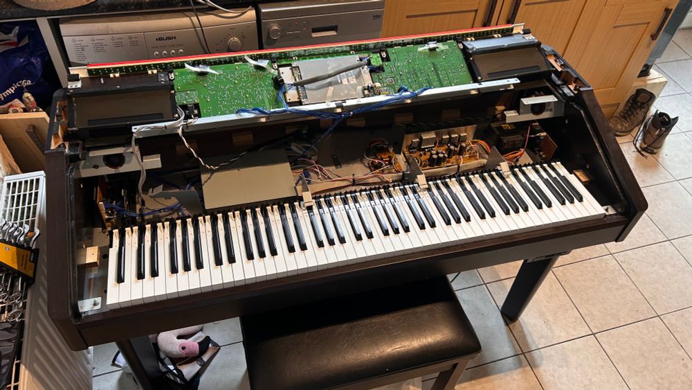 Digital piano (Clavinova) half disassembled with keyboard exposed and digital panel removed