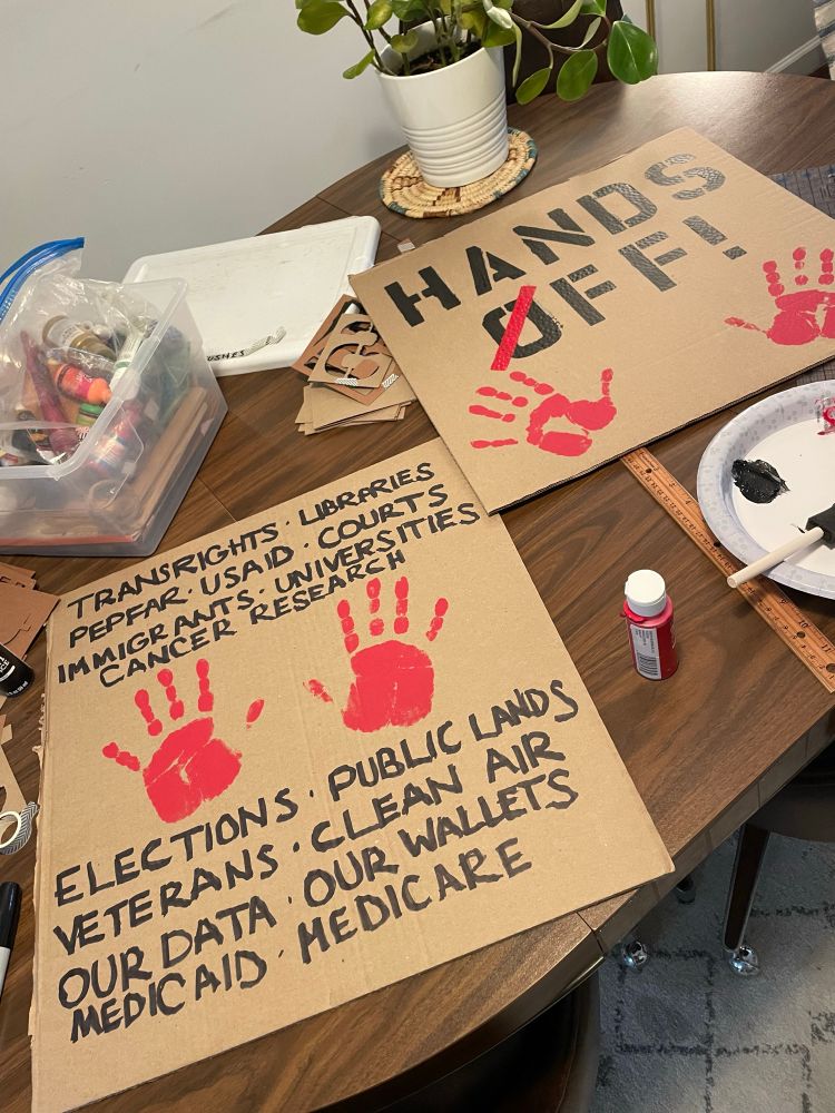 A protest sign reading “Hands off” with two red handprints, and then “trans rights, libraries, PEPFAR, USAID, courts, immigrants, universities, cancer research, elections, veterans, clean air, our data, our wallets, Medicaid, Medicare.”