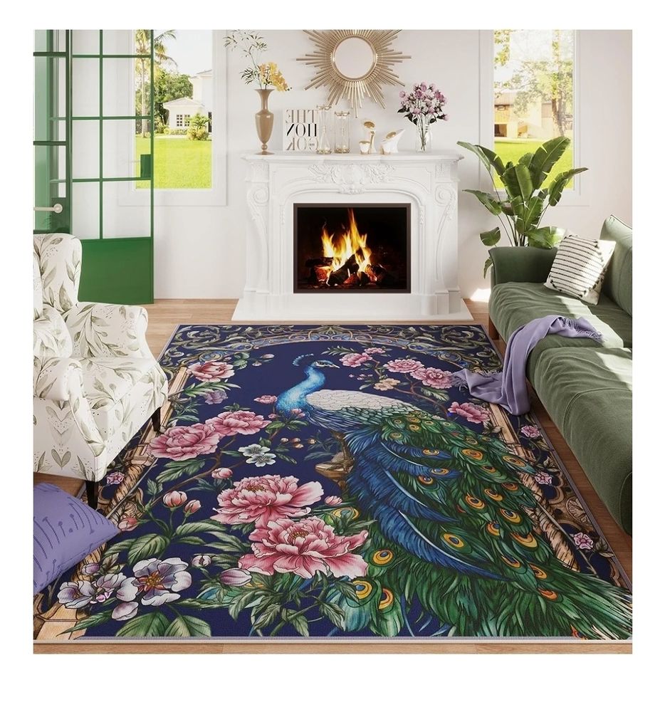 Staged pic of a large, colorful area rug in a living room.  The rug has a navy blue background, and in the middle is an elegant male peacock with beautifully long plumage.  He's surrounded by  pink flowers of varying sizes and an intricate wooden arch. 