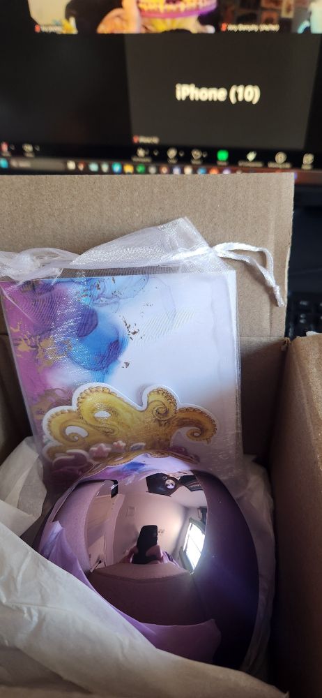 A brown box open at the top. Inside is a lavender metallic egg and a light pink bag of goodies. 