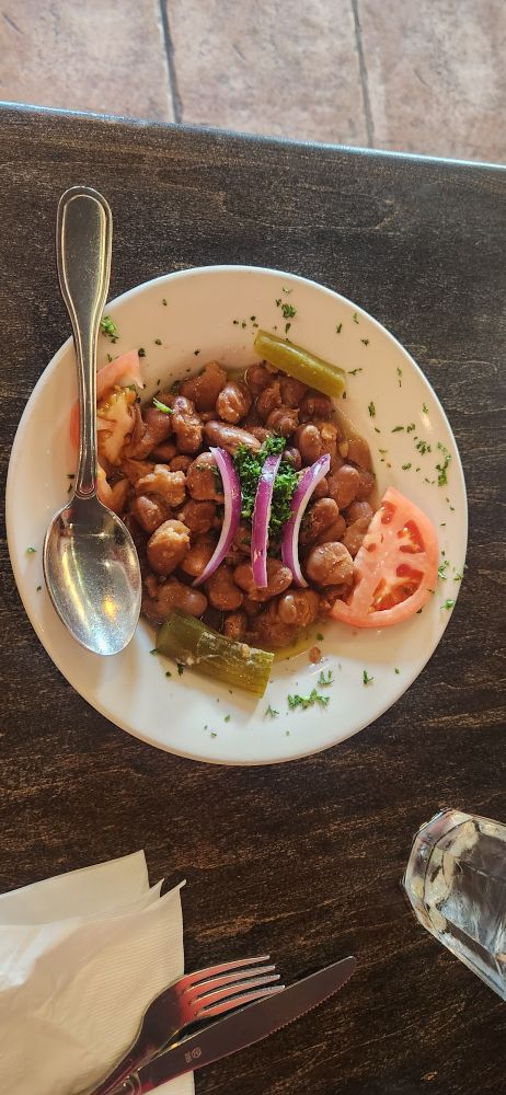 A bowl of ful moudamas (fava beans) sitting on a restaurant table.