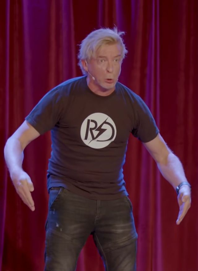 Rhys Darby in the middle of his robot impression.