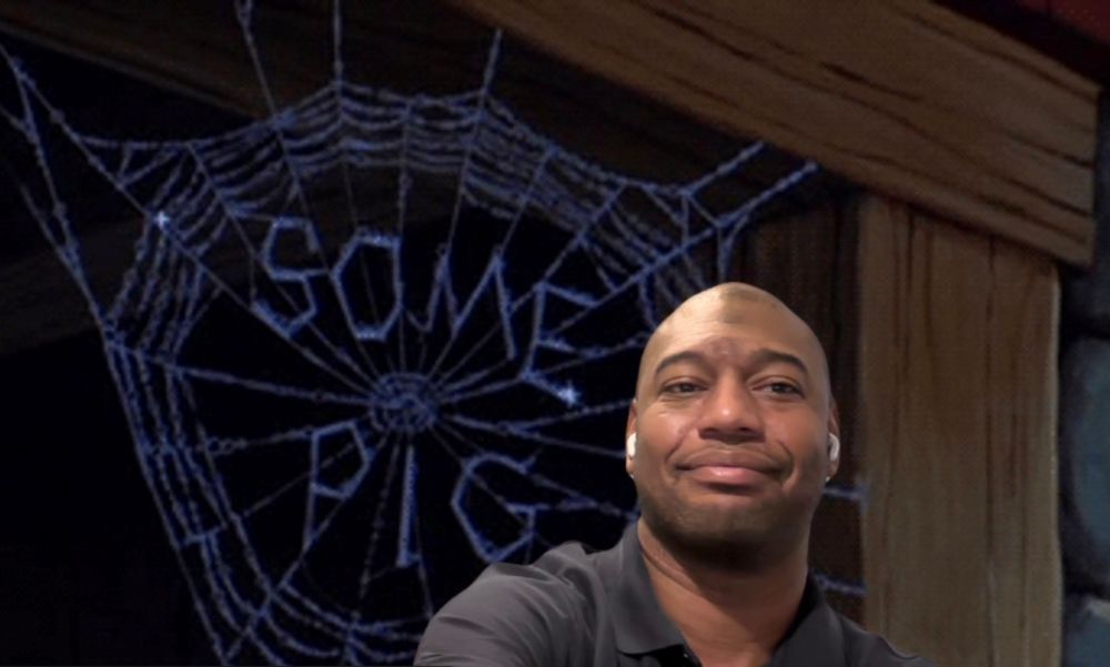 Man standing in front of a large cartoon spider web that says “some pig” a reference to Charlotte’s web since the man in the picture is named Wilbur