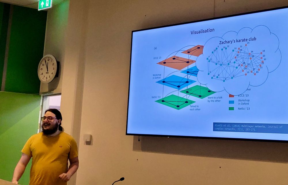 An "action shot" of @arash.network during his award winning talk, with a TV in the background showing the famous karate club network
