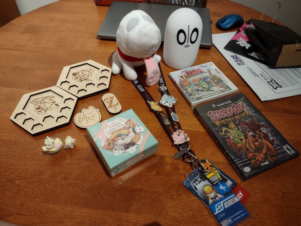 PAX haul with some DnD coasters, wooden magnets, tiny Alcremie and Milcery, Frenemy Pastry Party (a pasty making card game), Polterpup plush, Nabstablook lamp, Triforce Heroes (for Medz), and Scooby Doo Mystery Mayhem