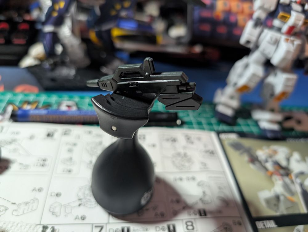 The Beam Rifle, post painting on my mini stand used for painting. It was originally a deep purple, decided to paint it a dark gray compared to the photos in the manual.