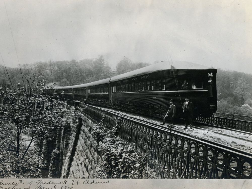 A view on a B&O viaduct shows off the very advanced boat-tail observation car, 30 years ahead of them entering service elsewhere. 