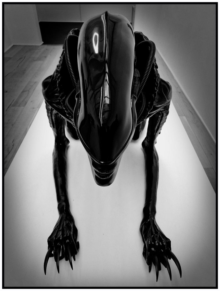 Image en noir et blanc d'un sculpture de xénomorphe noir par Hans Ruedi Giger vu de dessus.