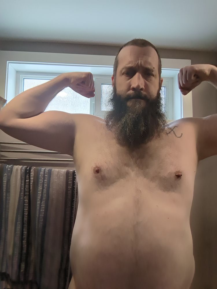 Shirtless bearded bear taking a selfie in a mirror