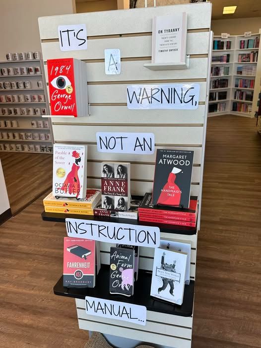 Image of a library book display labeled:
"It's A Warning Not An Instruction Manual"
The books on display are:
'On Tyranny, Twenty Lessons From The 21st Century'
'1984'
'A Handmaids Tale'
'Diary of Anne Frank'
'Parable of The Sower'
'Fahrenheit 451'
'Animal Farm'
'Brave New World'