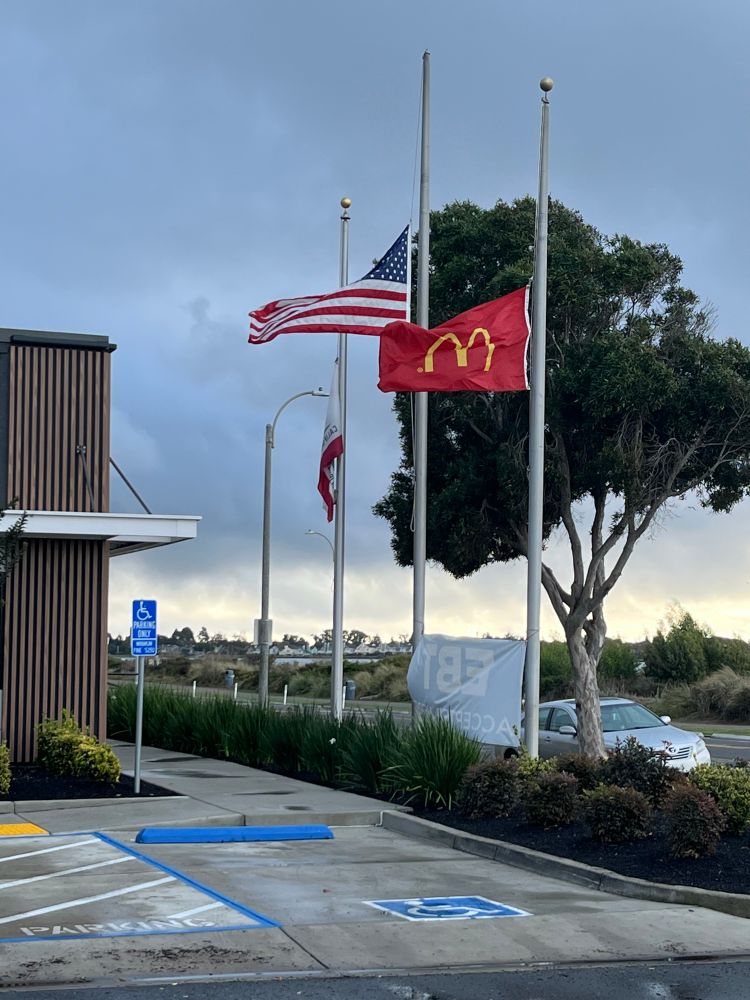 Outside of a McDonald’s, the Golden Arches and American flags fly at half staff. 