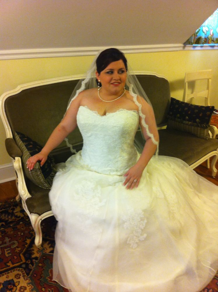 Me in my wedding dress 13 years ago today. I’m sitting on a bench, and the ivory dress has a strapless sweetheart neckline, drop waist, and lace overlay. I’m wearing pearls and have a simple waist-length veil with a scalloped lace trim. The corset + bodice give me the figure I’ve always wish I really had—even seated!