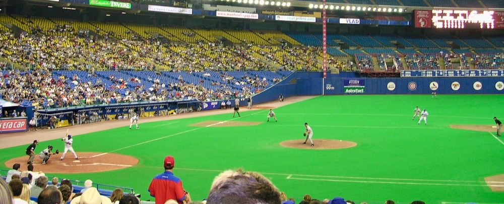 Vlad Guererro Sr. bats for the Expos in 2003 inside the Olympic Stadium of Montreal. The ballfield has bright green turf and its stands are about 1/3 full.