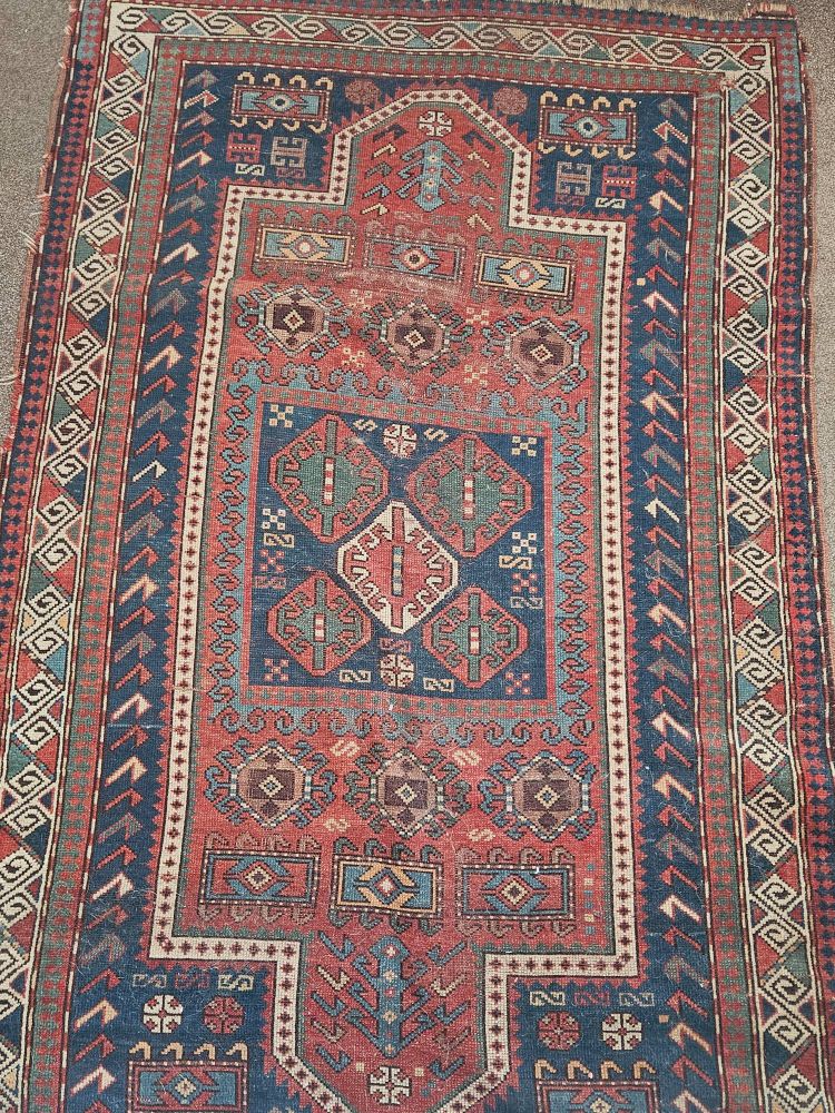 A rug with varying patterns in cream, blue and red colours