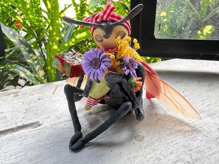 Sculpture of a ladybug holding flowers and chocolates