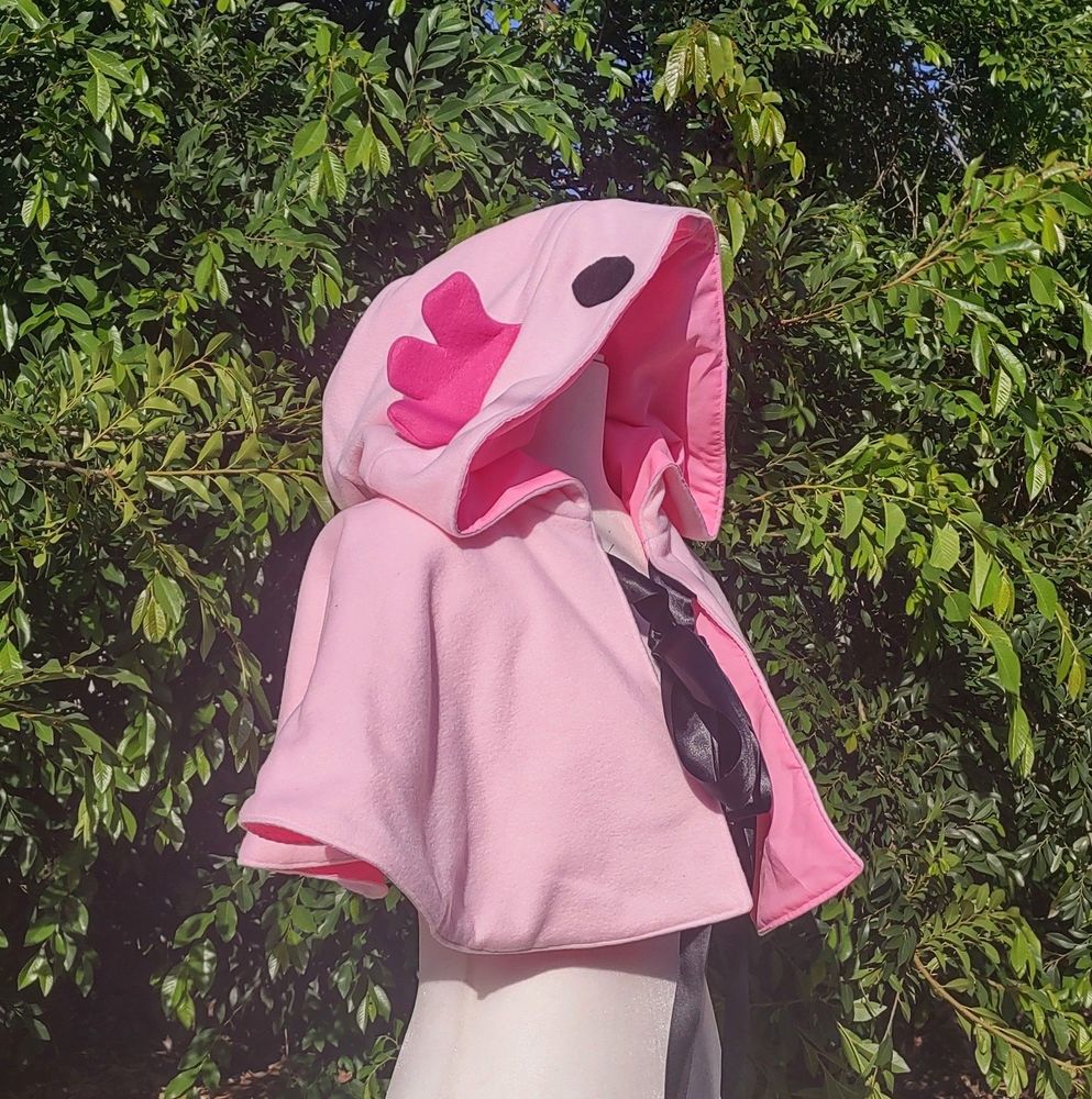 Shoulder length cape made to look like an axolotl. Cape is pink with dark pink gills and has black felt eyes. Cape closes with black satin ribbon.
