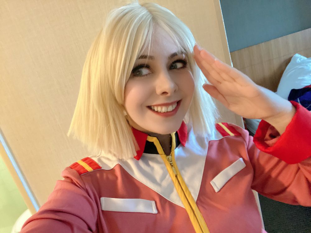 Myself as Sayla Mass from Mobile Suit Gundam. Pale blonde voluminous bob over a pink sci-fi uniform trimmed in white, red, gold, and black 