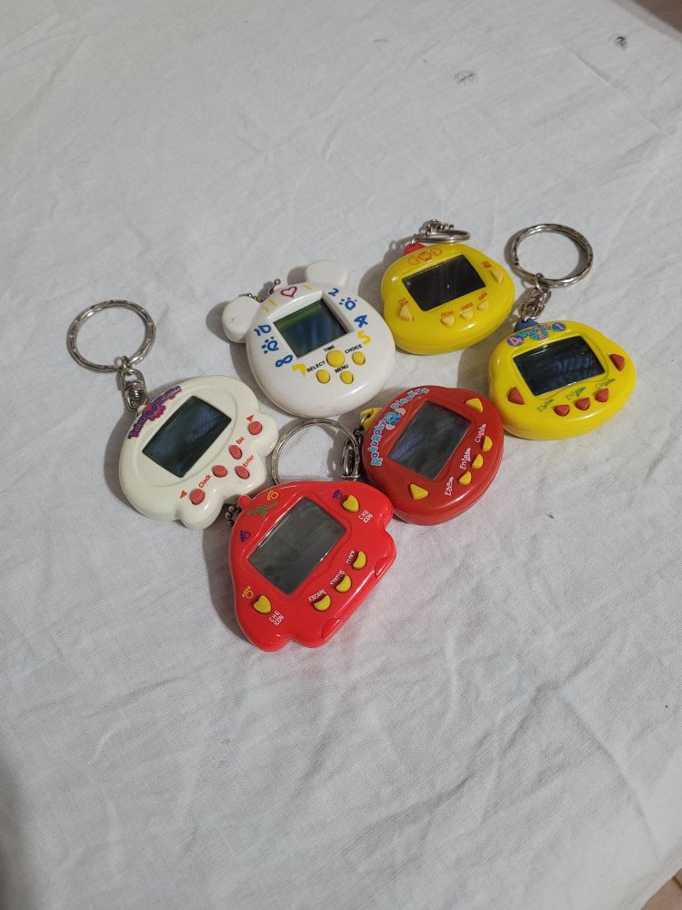 Um monte de bichinho virtual/tamagochi. 2 amarelos, 2 vermelhos e 2 brancos. Um tem orelha de ursinho e o outro parece uma caveira 