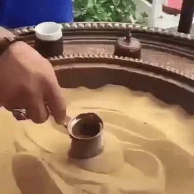 Video på någon som gör traditionellt turkiskt kaffe genom att dra ett kärl med kaffe över stekhet sand, så att det kokar och bryggs. 