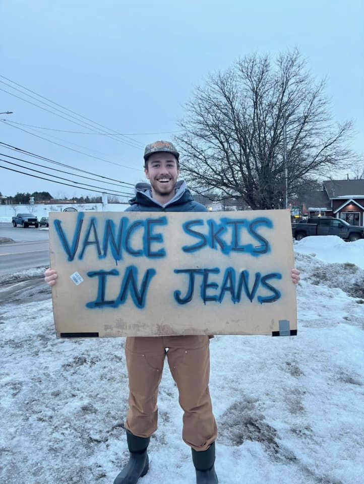 photo of a protester holding a sign that says "Vance Skis In Jeans"