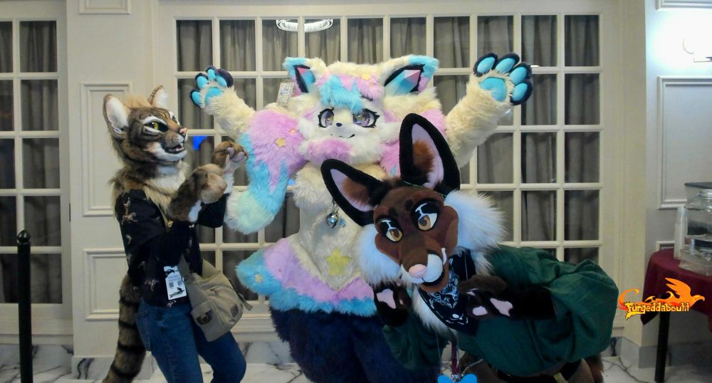 Three fursuits, Junebug the tabby cat, pastel Braixen, and Basil the fox posing indoors. 