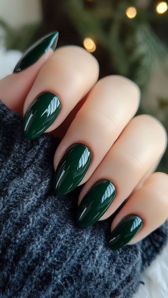 An elegant display of dark forest green nail art featuring intricate floral designs and shimmering a
