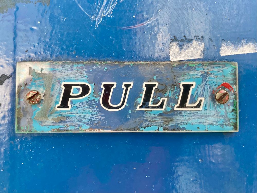 Small sign on royal blue door. The word ‘Pull’ in all caps italics - black outlined in white. Printed on clear perspex. 1960s?