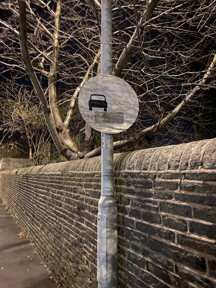 Faded road sign under harsh LED street lighting