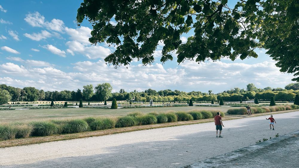 A father and son playing badminton in the garden of Fontainebleau Palace