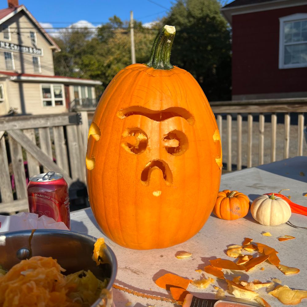 Photo of a carved pumpkin with a cute and silly face.
