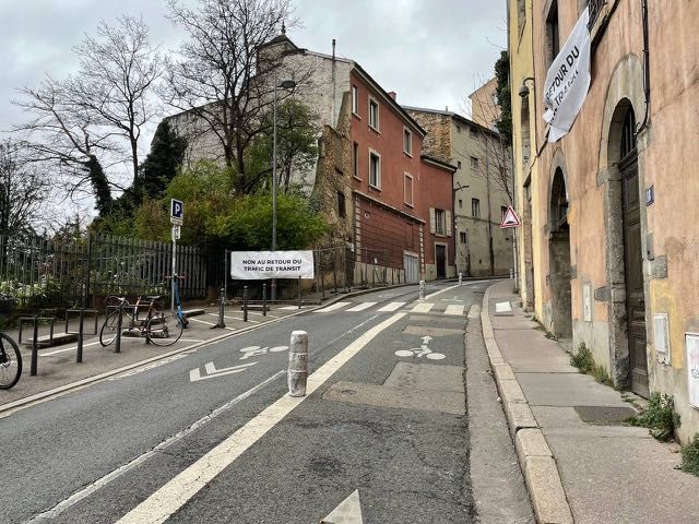 On voit 2 banderoles: une à la fenêtre d'un habitant de chemin neuf, une seconde sur des barrières de chantier. Inscription dessus: "Non au retour du trafic de transit"