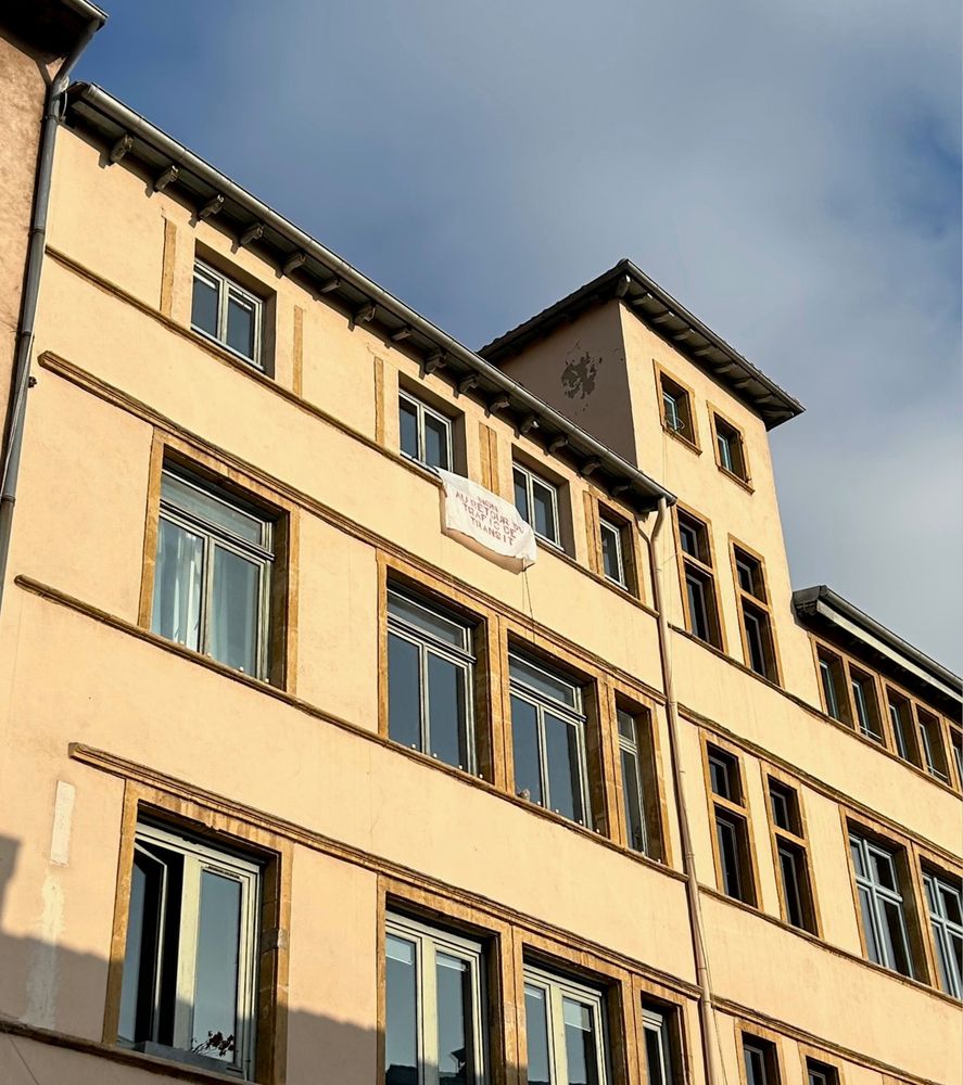 Une banderole "Non au retour du trafic de transit" à la fenêtre d'un immeuble ancien sur montée du chemin neuf