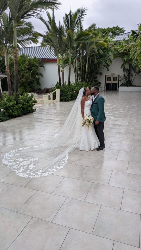 KC and Khea kissing outdoors as Khea's long wedding dress train creates a heart on the ground beside them.